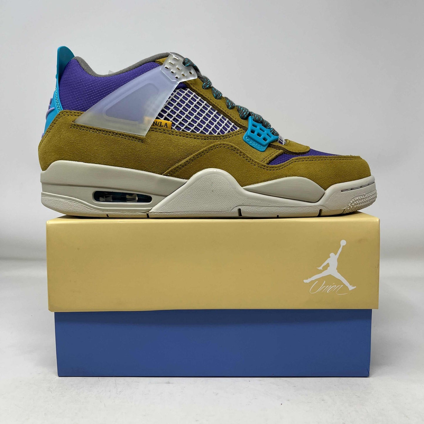 Jordan 4 Retro SP 30th Anniversary Union Desert Moss sneaker in brown, purple, and blue on stacked Jordan shoeboxes