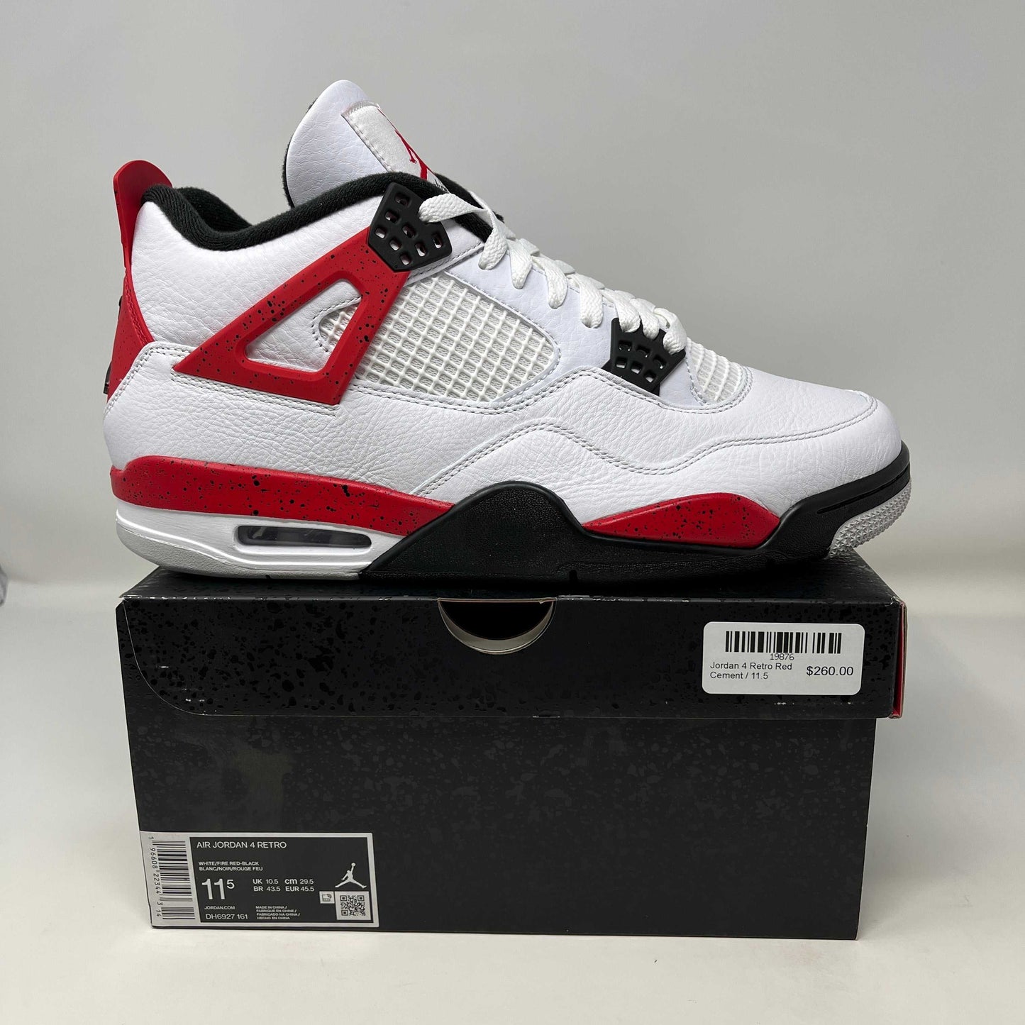 Jordan 4 Retro Red Cement sneaker in white, red, and black on black box with price tag.