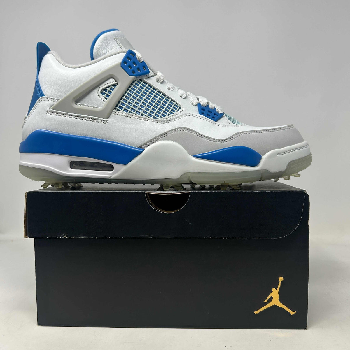 Jordan 4 Retro Golf Military Blue sneaker in white leather with royal blue accents, mesh panels, and spiked golf outsole.
