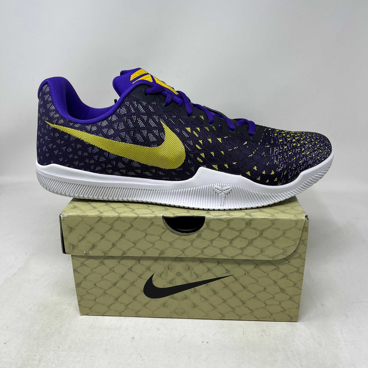 Nike basketball shoe in Nike Mamba Instinct Court Purple, with a black patterned mesh upper, purple trim, yellow swoosh and white sole.