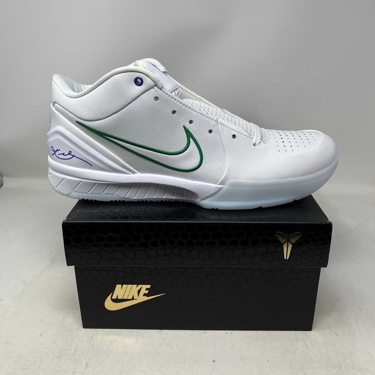 Nike Kobe 4 Protro basketball shoe in white leather with a green outlined Swoosh, perforated toe, and purple signature details.