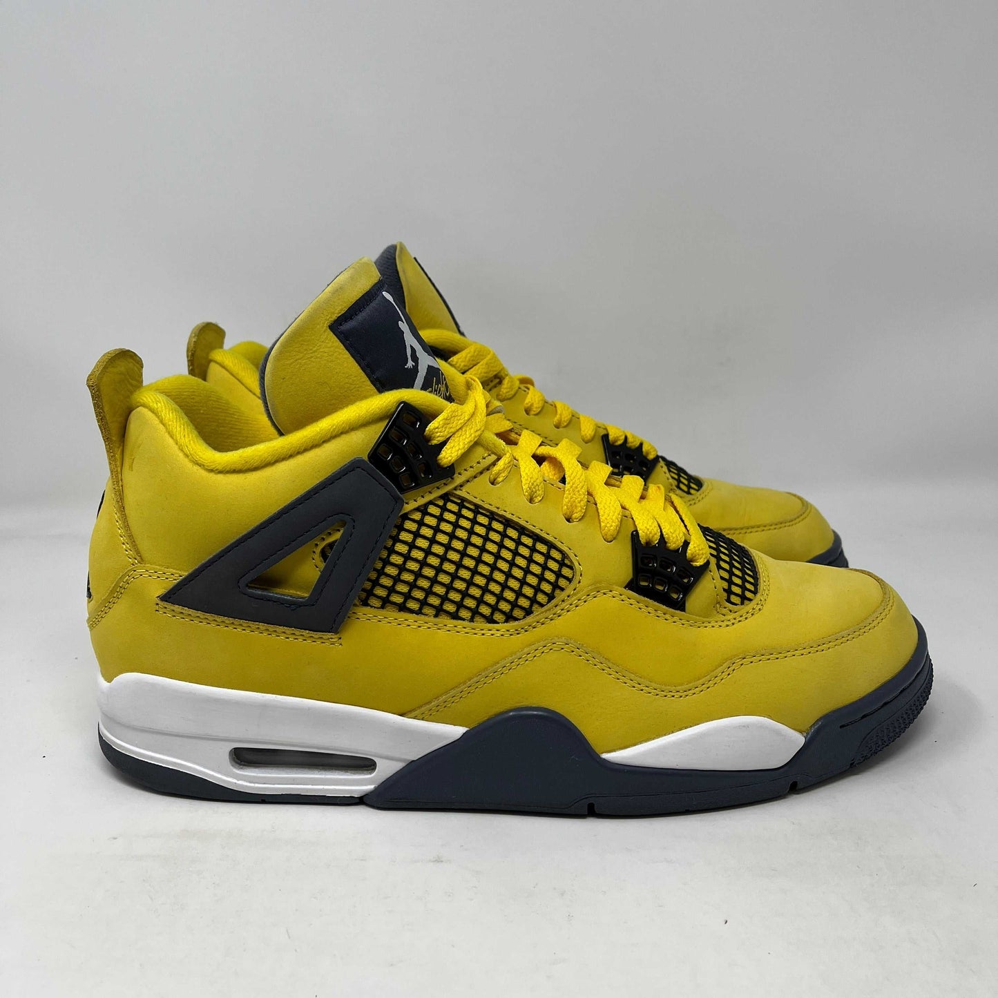 Used yellow Jordan 4 Retro Lightning sneakers with black and white accents, no box shown