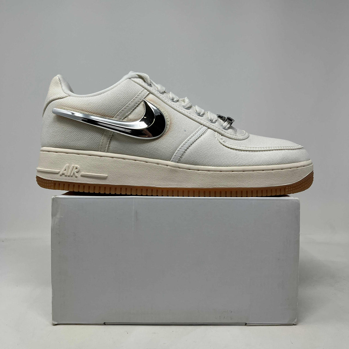 Nike Air Force 1 Low sneaker in off-white textured leather with a glossy black Swoosh, cream sole and gum outsole.