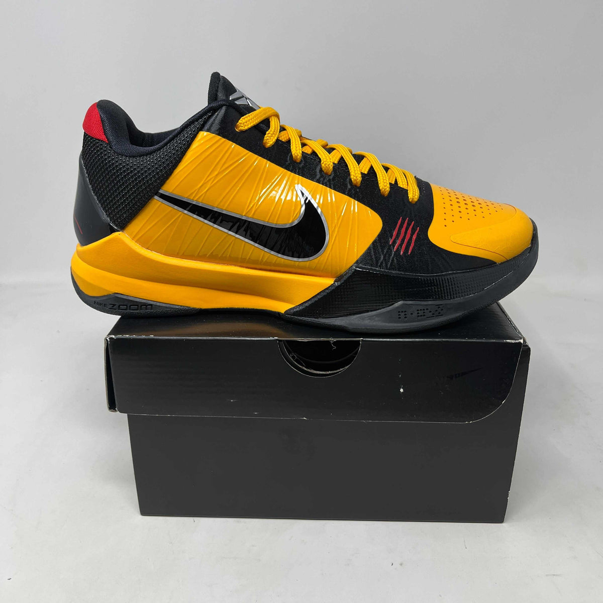 Nike Kobe 5 Protro Bruce Lee basketball shoe in yellow and black synthetic leather, with red accents, laces and Swoosh.