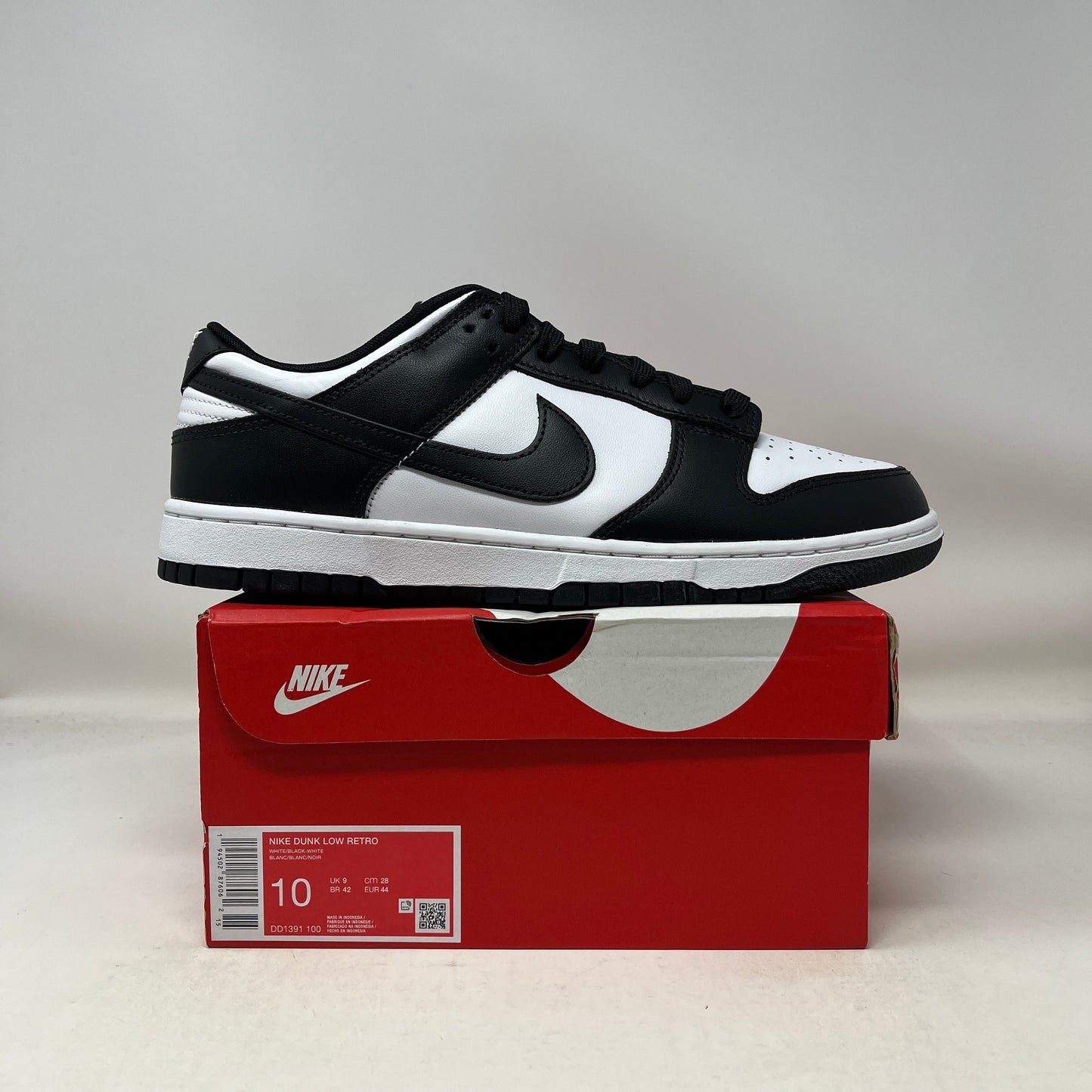 Nike Dunk Low Retro White Black Panda sneaker on red Nike box in size 10