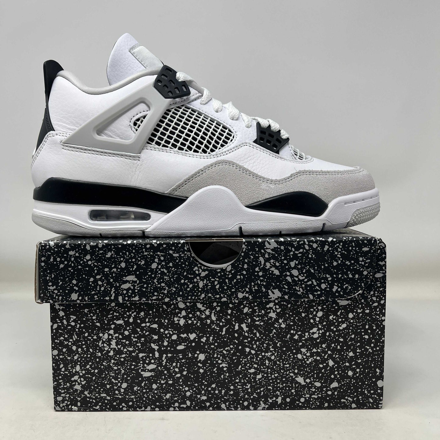 Jordan 4 Retro Military Black sneaker in white, black, and grey on black speckled shoebox