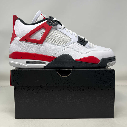 Jordan 4 Retro Red Cement sneaker in white leather with red cement speckling and black accents on a black shoe box.