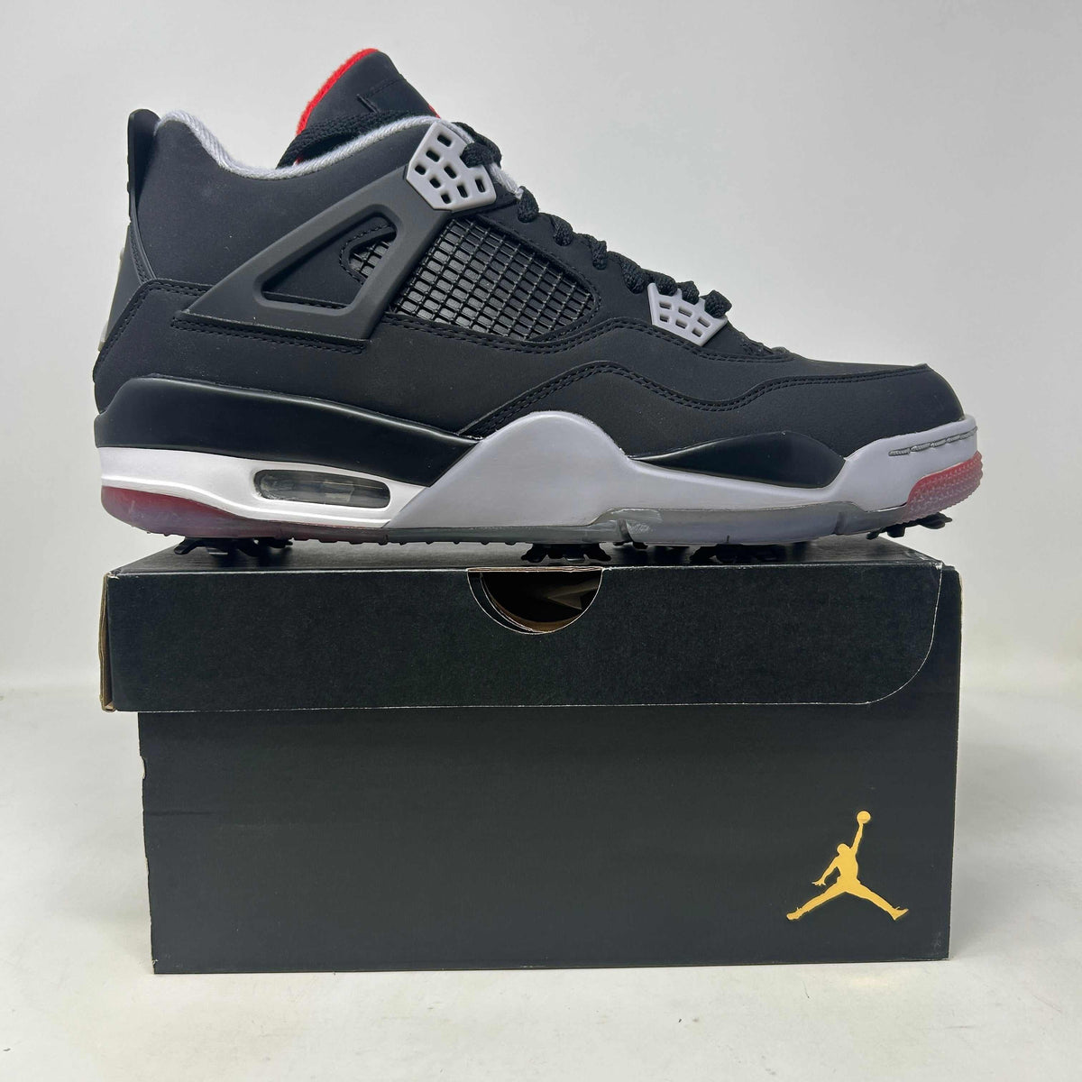 Jordan 4 Retro Golf Bred sneaker in black leather with mesh panels, grey accents, red details and golf traction sole.