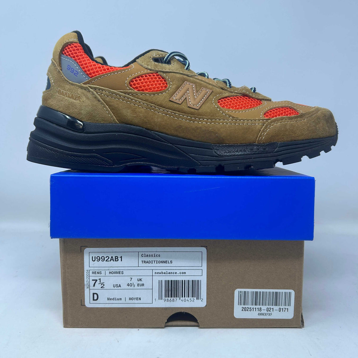 New Balance 992 sneaker in tan suede and orange mesh, with a navy sole, blue laces, and signature N logo.