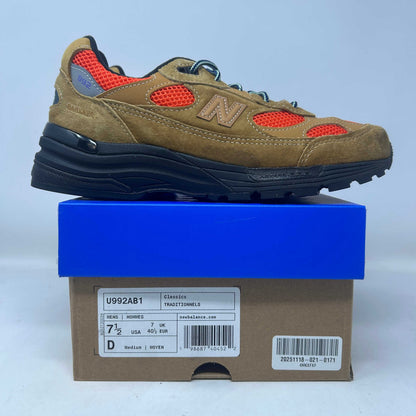 New Balance 992 sneaker in tan suede and orange mesh, with a navy sole, blue laces, and signature N logo.