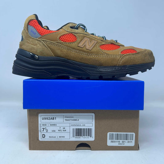 New Balance 992 sneaker in tan suede and orange mesh, with a navy sole, blue laces, and signature N logo.