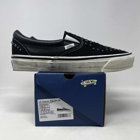 Vans LX Classic Slip-On 98 black leather skate shoe with silver studs, white side stripe, and scuffed gray sole.