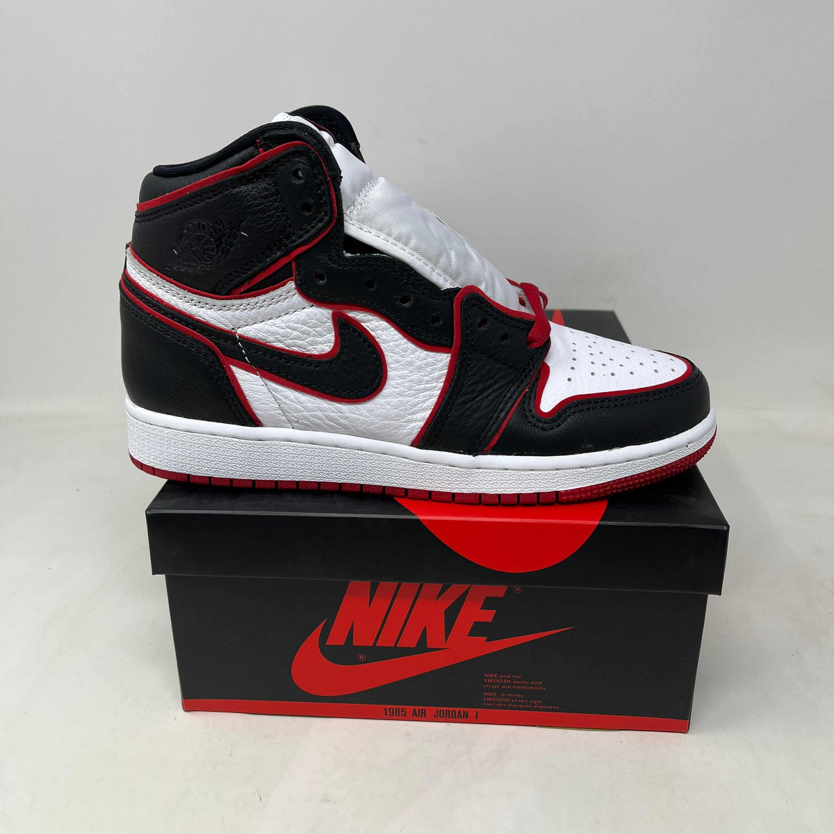 Jordan 1 Retro High Bloodline high-top sneaker in black, white, and red leather, with a Swoosh and Wings logo.